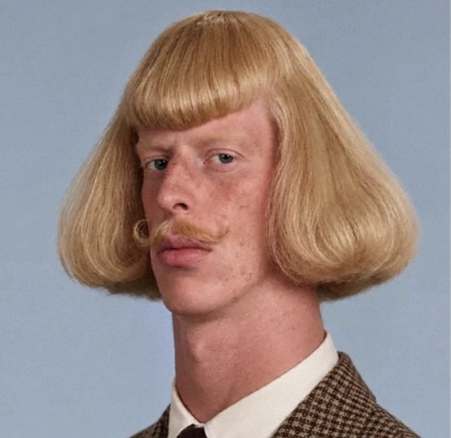 Jean Phil&rsquo;s studio portrait: blond bowl cut, curled mustache, houndstooth jacket, as used in the Binance Intern post